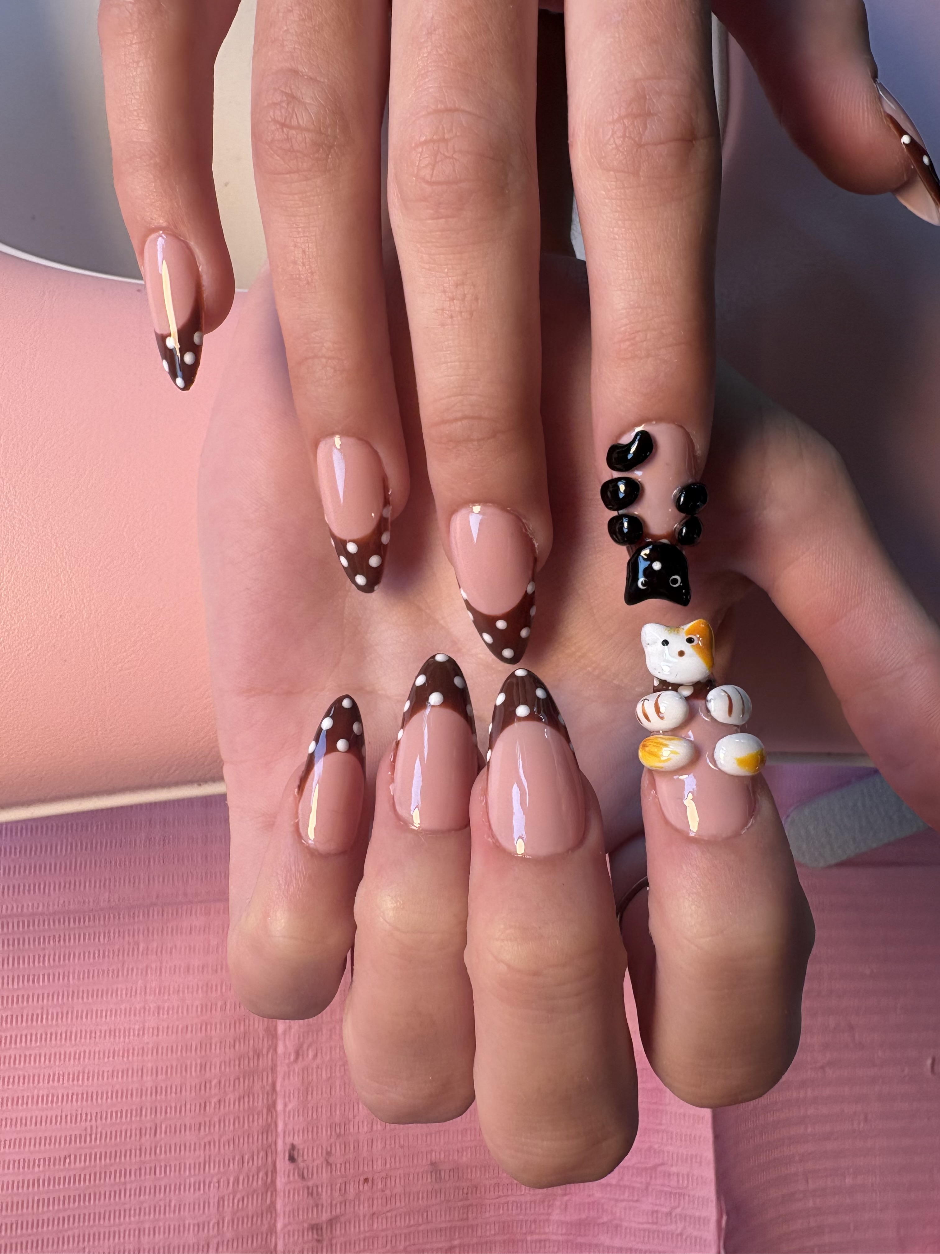 Brown French tips with polka dots and a 3D sculpted gel cat accent nail