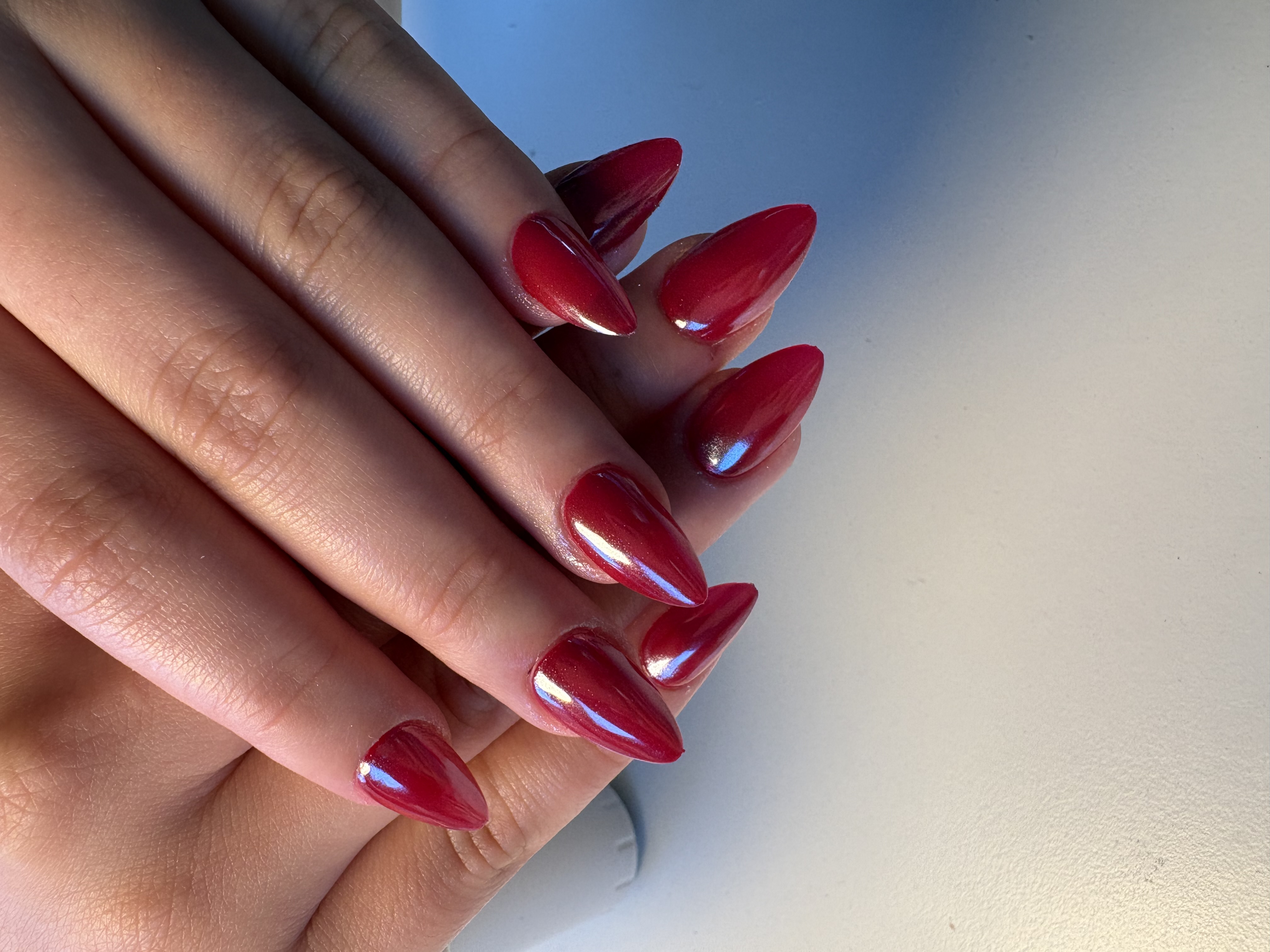Solid deep red glossy almond nails with a classic high-shine finish