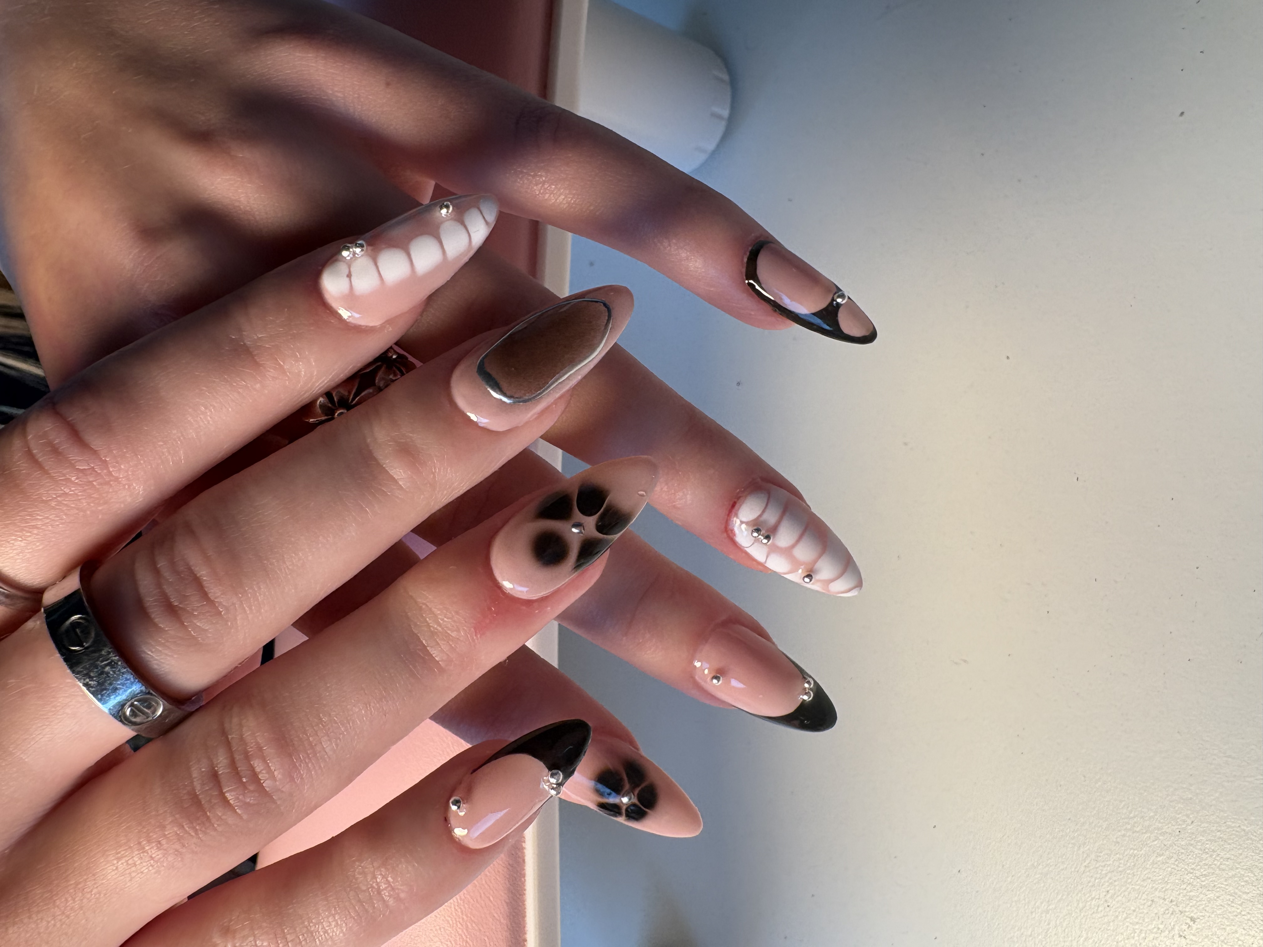 Nude nails with black French tips, flower cutouts, and a marble bone-texture accent