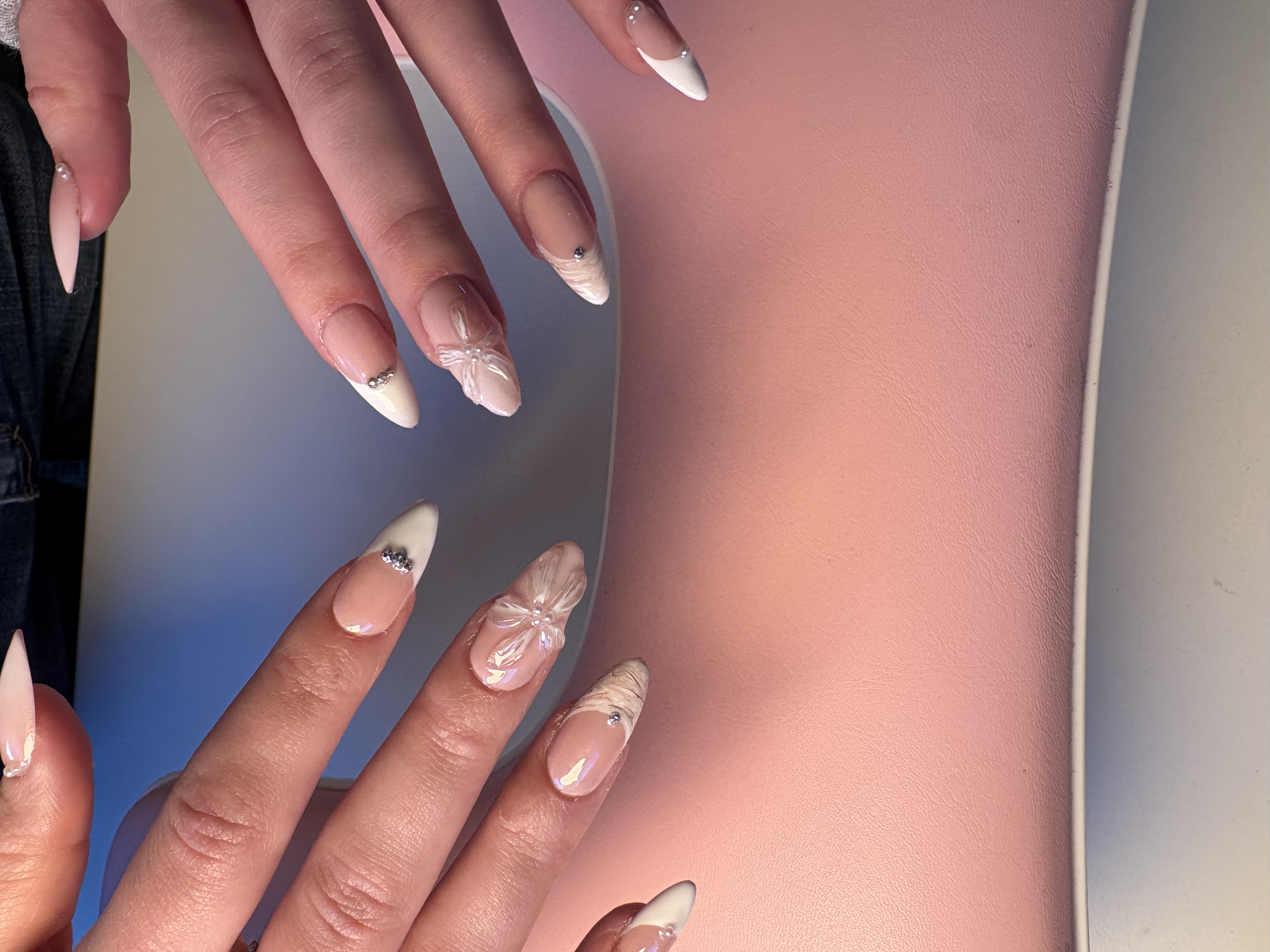 Nude almond nails with white French tips and 3D sculpted rhinestone flower accents