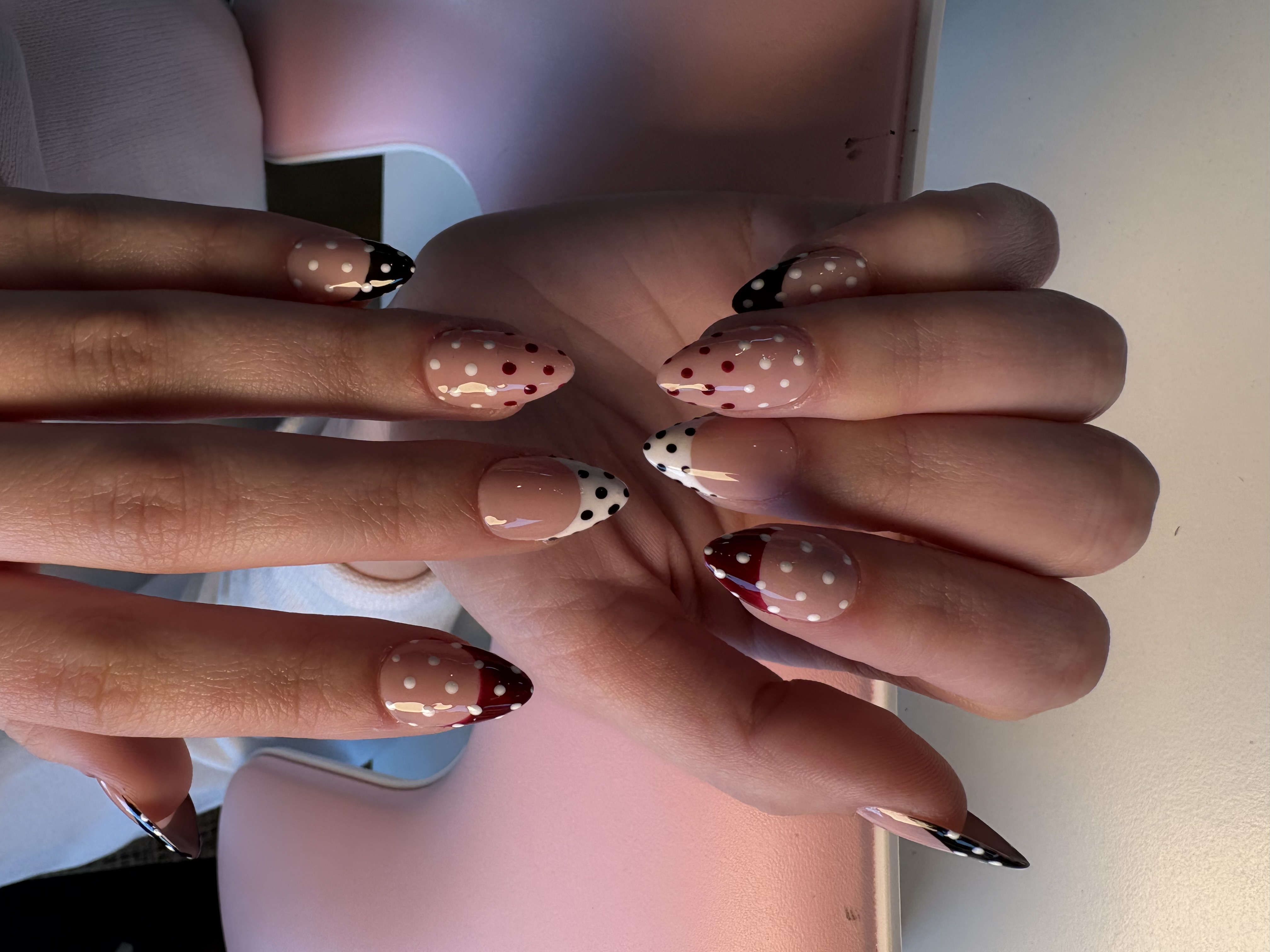Nude stiletto nails with black French tips and red-and-white polka dot accents