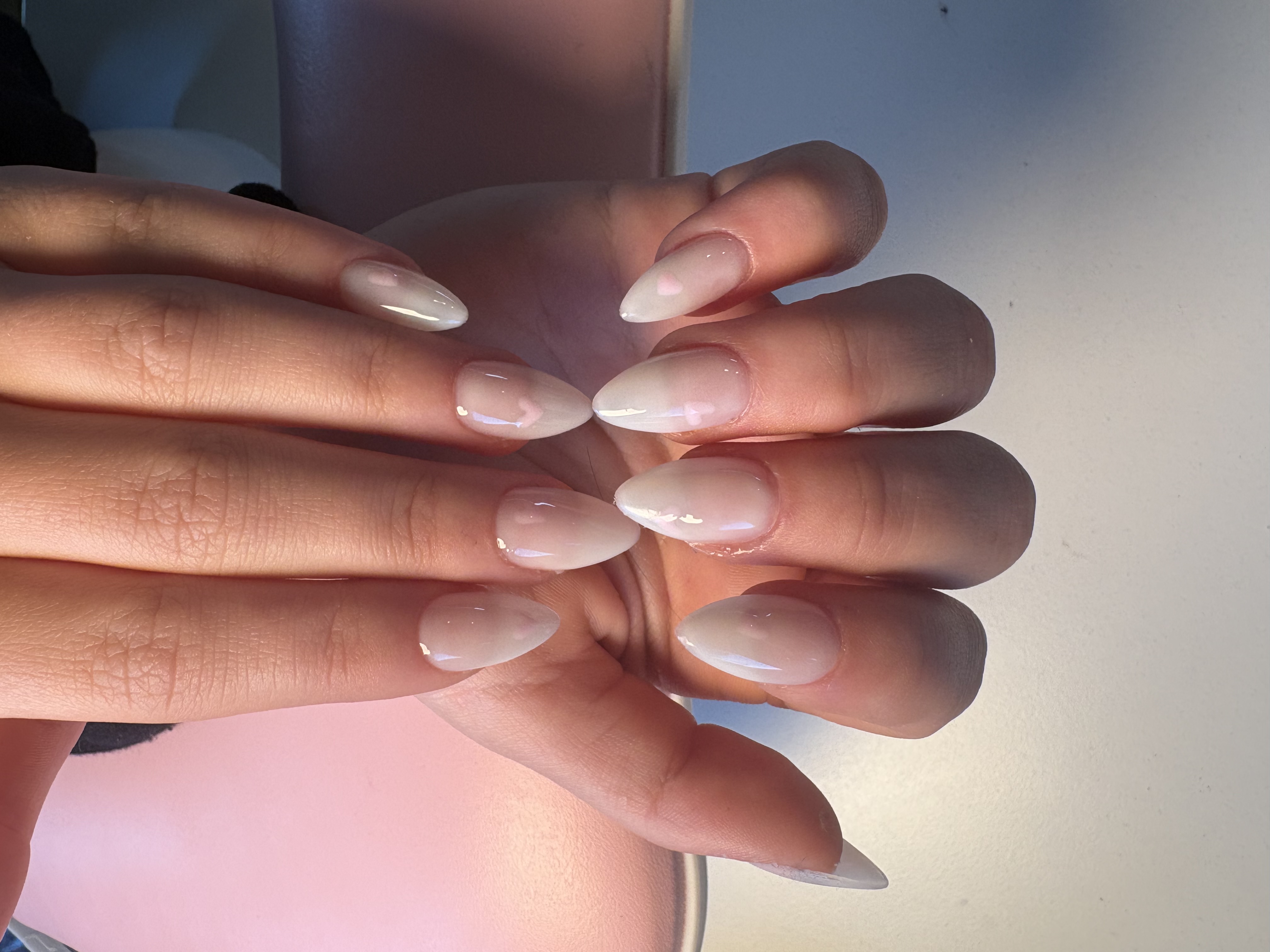 Sheer nude almond nails with two tiny white heart accents