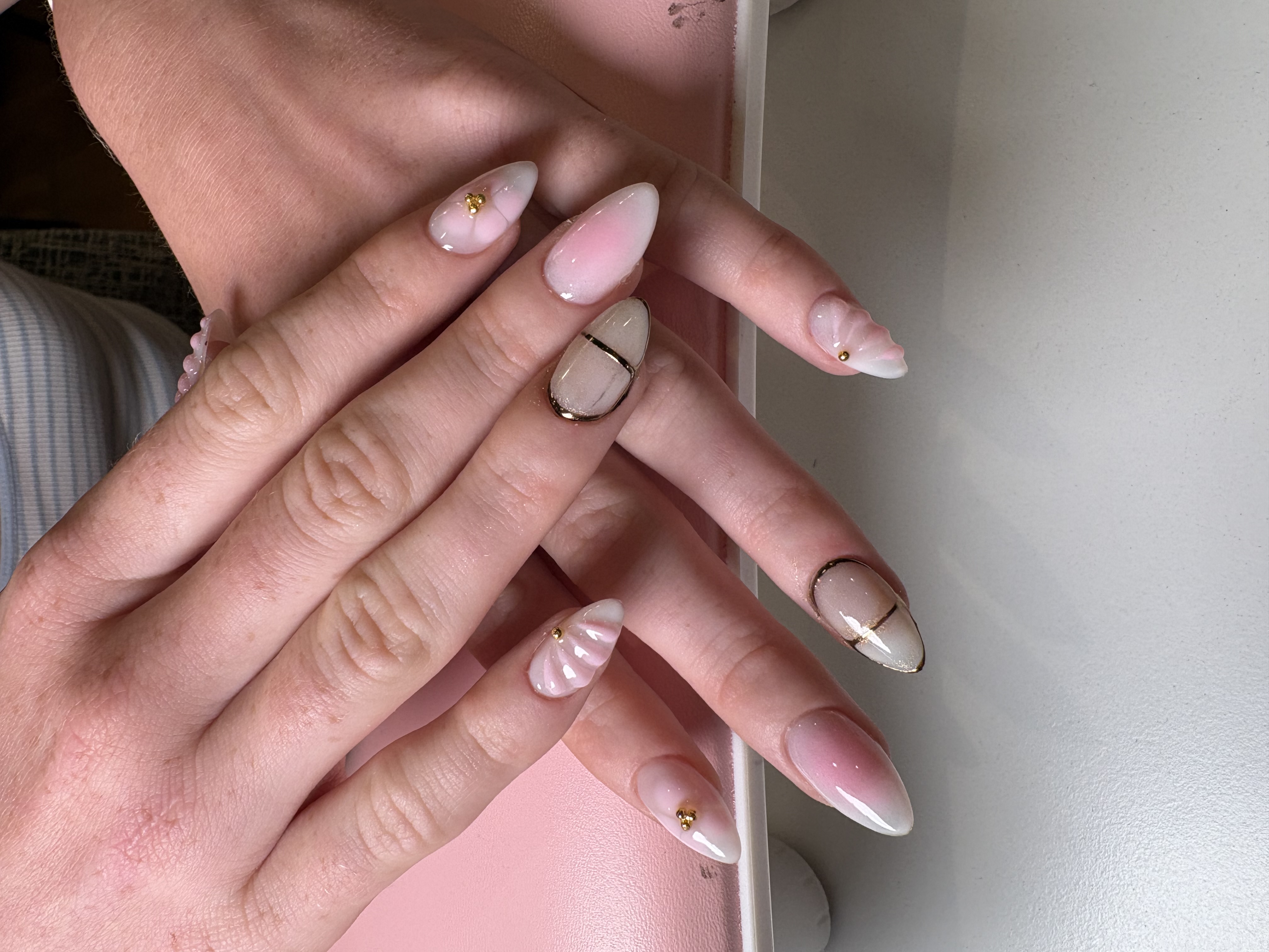 Nude almond nails with gold chrome lines and 3D sculpted shell accents