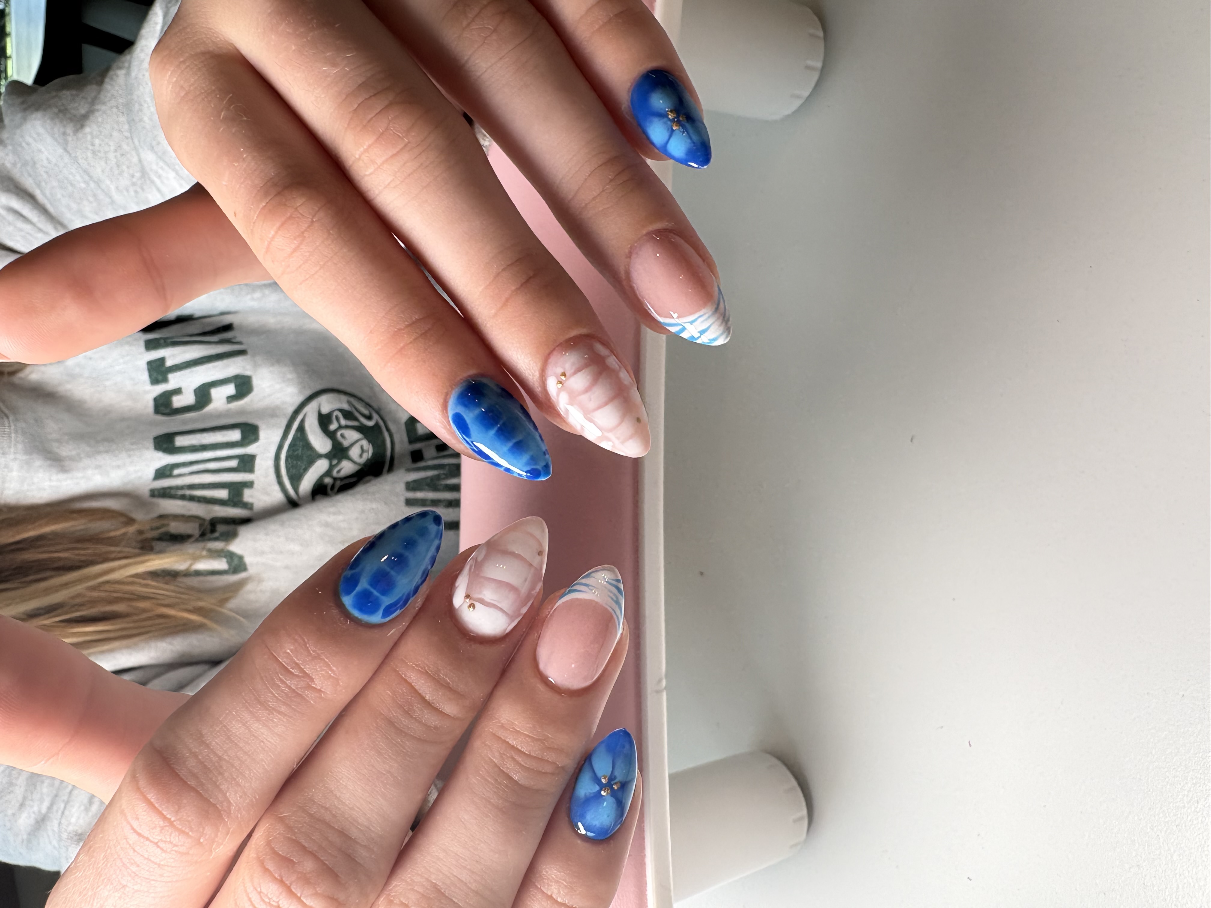 Blue marbled almond nails with gold flakes and a 3D sculpted shell accent