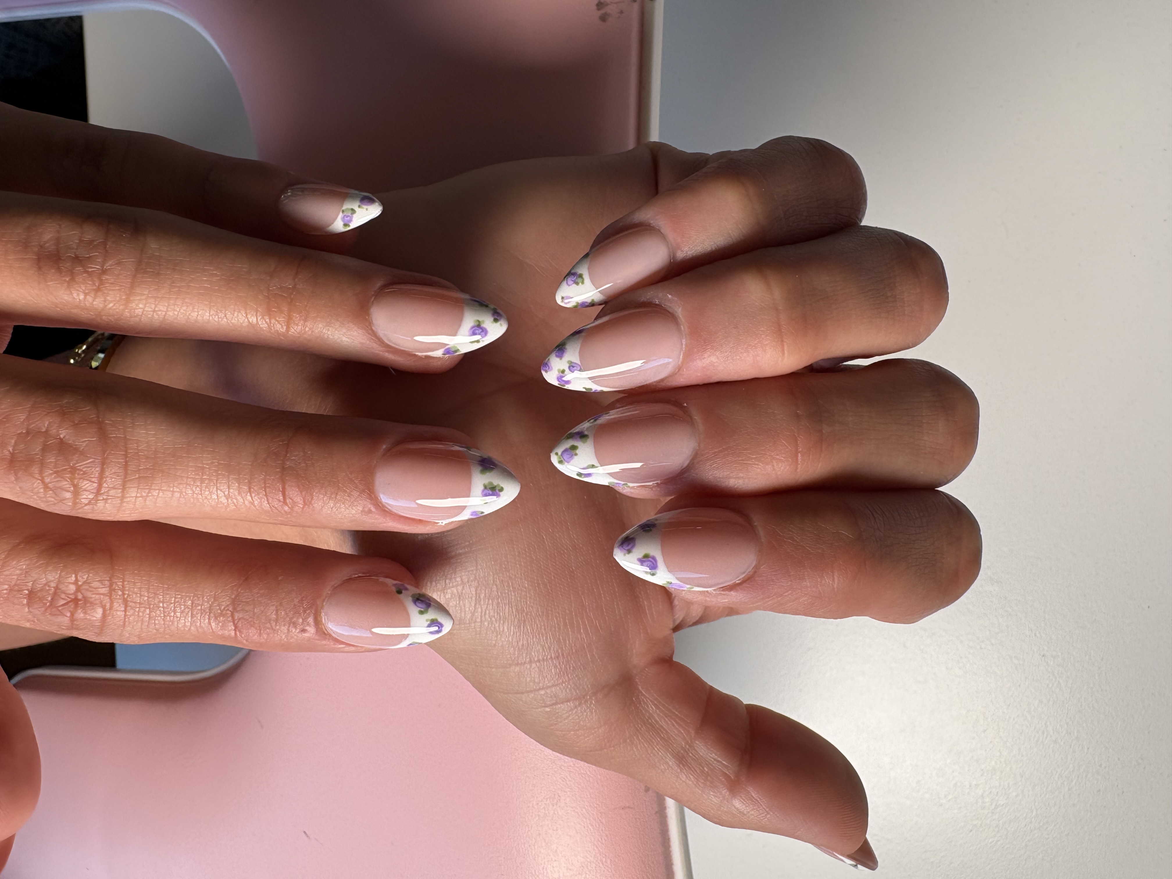 Nude nails with white French tips and hand-painted purple flower accents