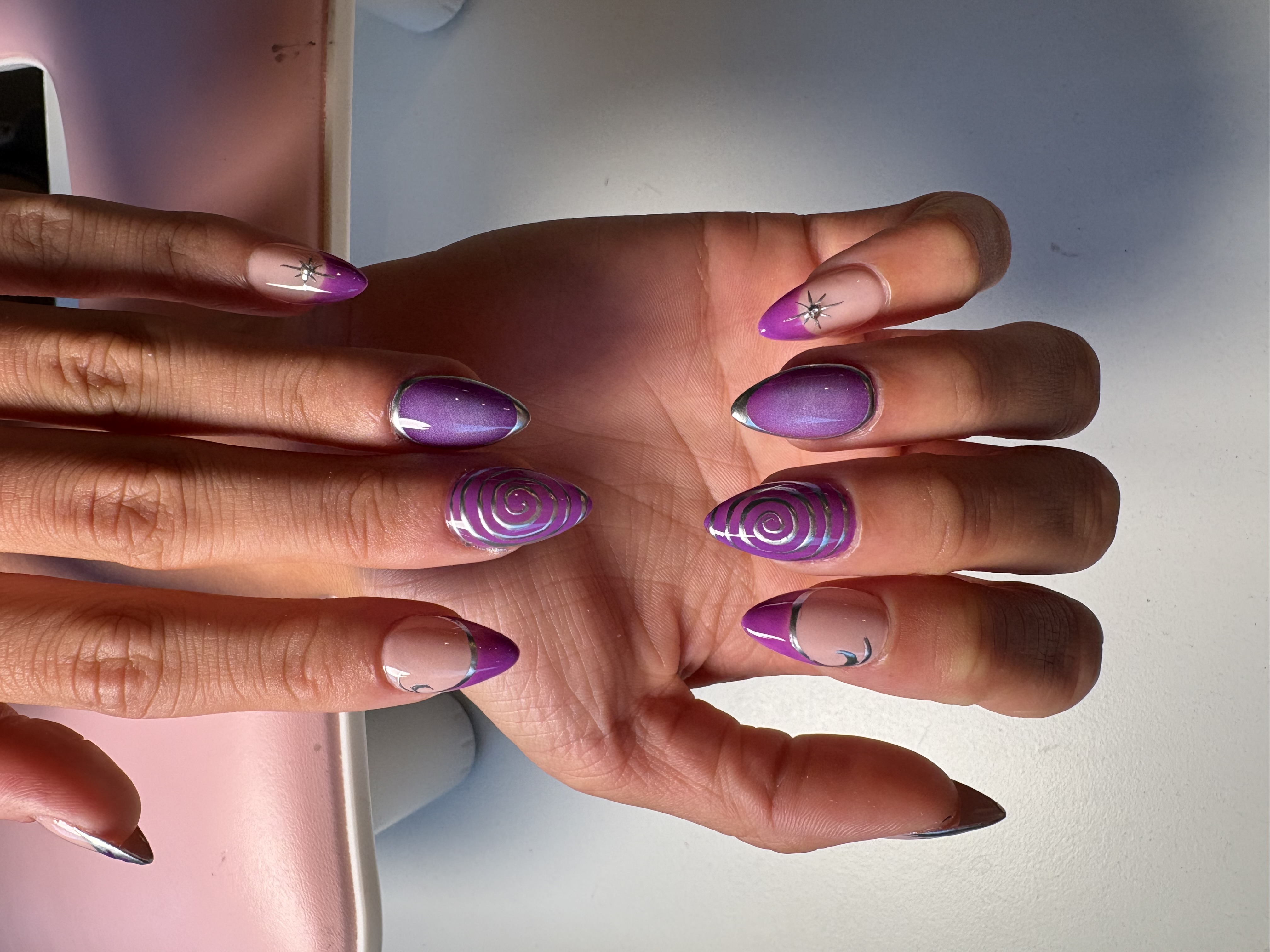 Purple chrome ombre nails with silver spiral linework and rhinestone star accents