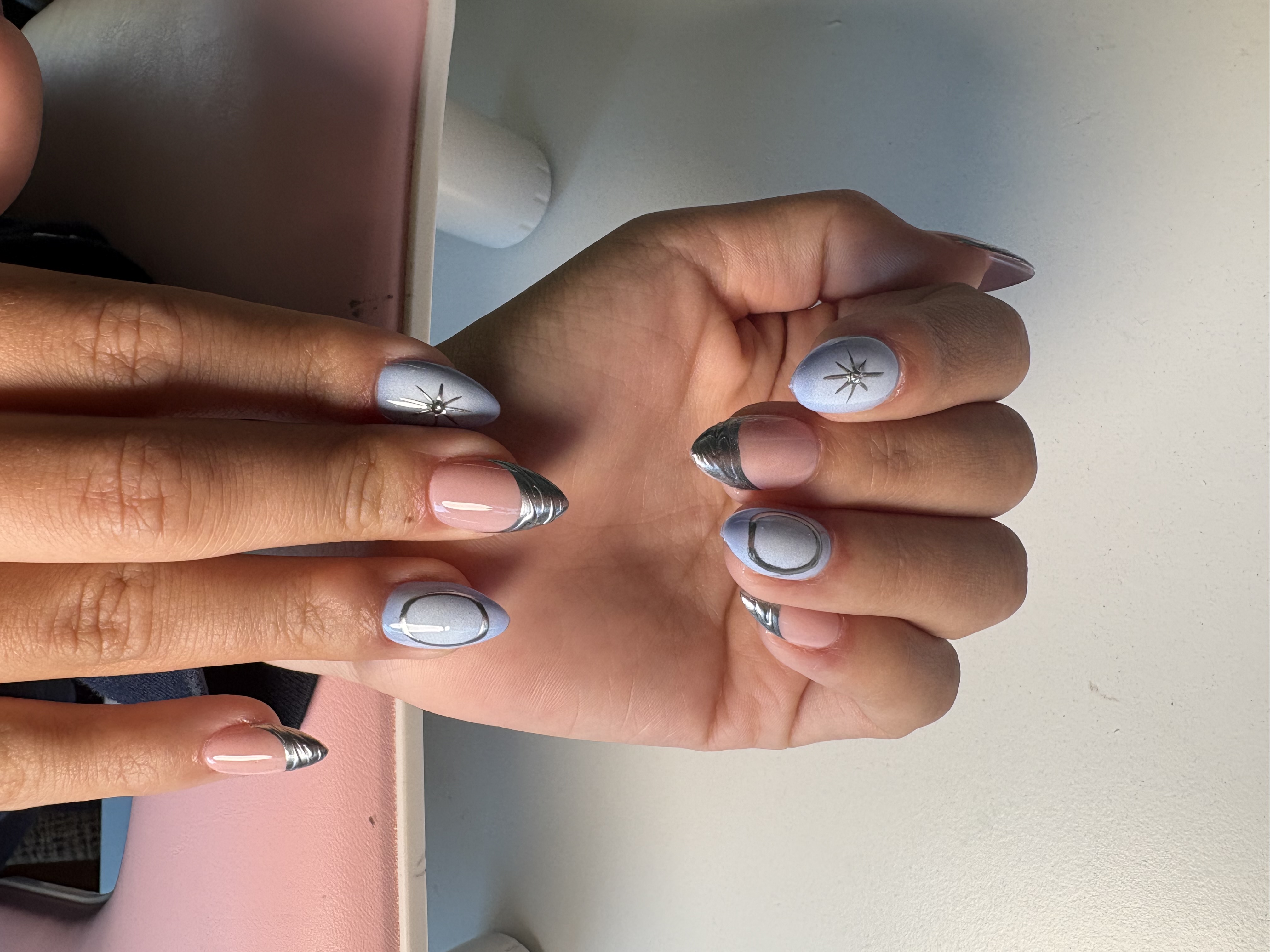 Periwinkle almond nails with chrome silver French tips, star charms, and swirl linework