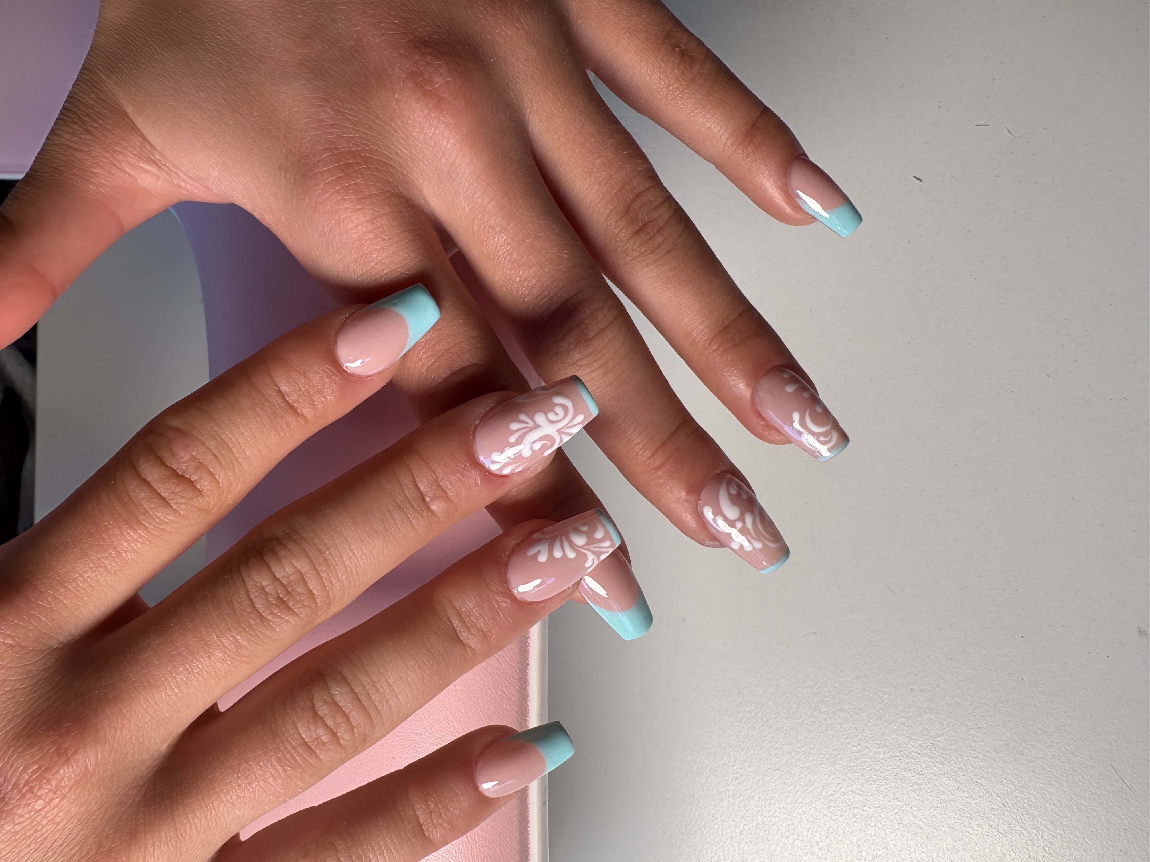 Nude almond nails with 3D sculpted flower petals, gold vine linework, and chrome tips
