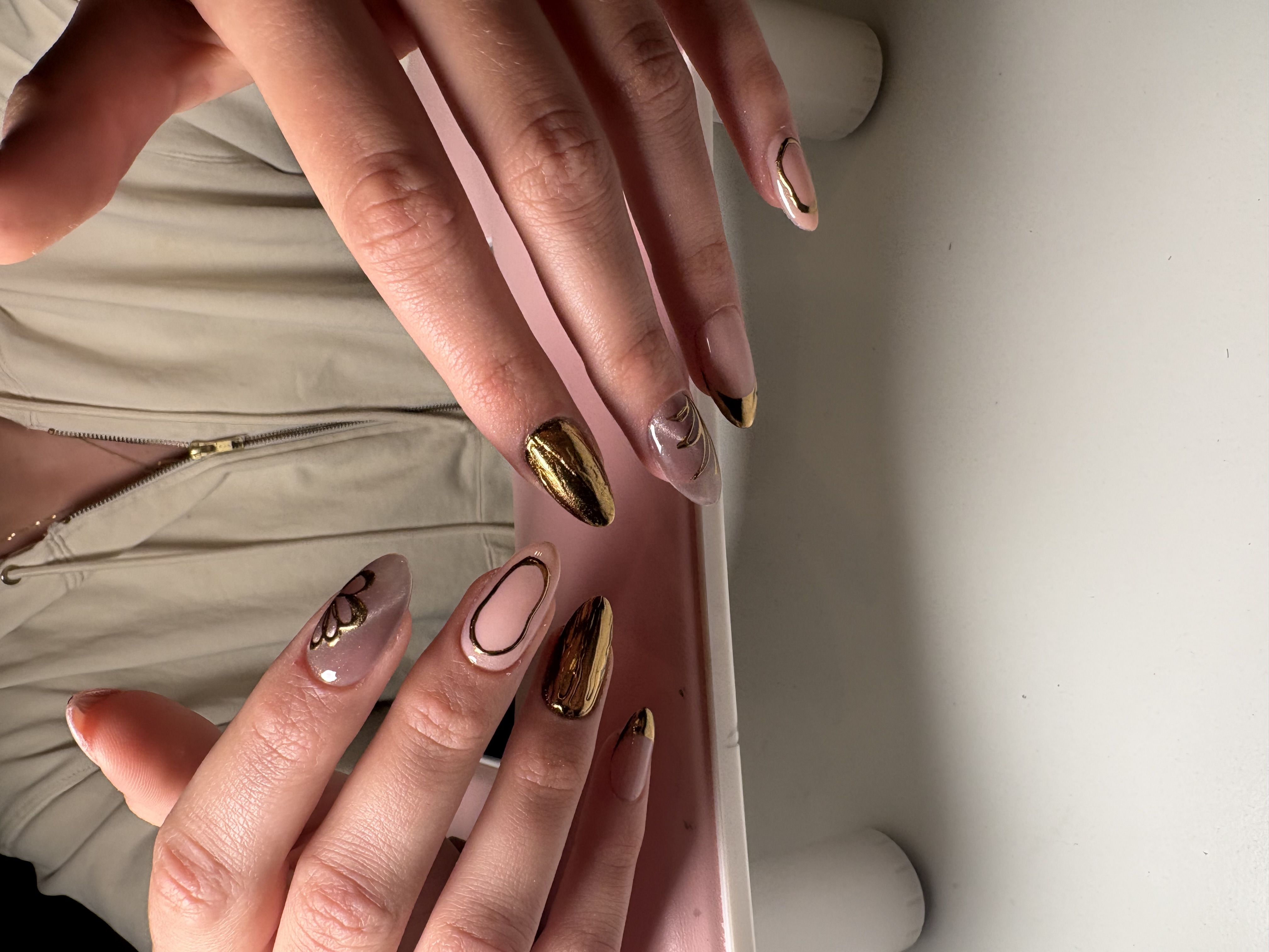 Nude almond nails with chrome gold accent nails and fine gold swirl linework