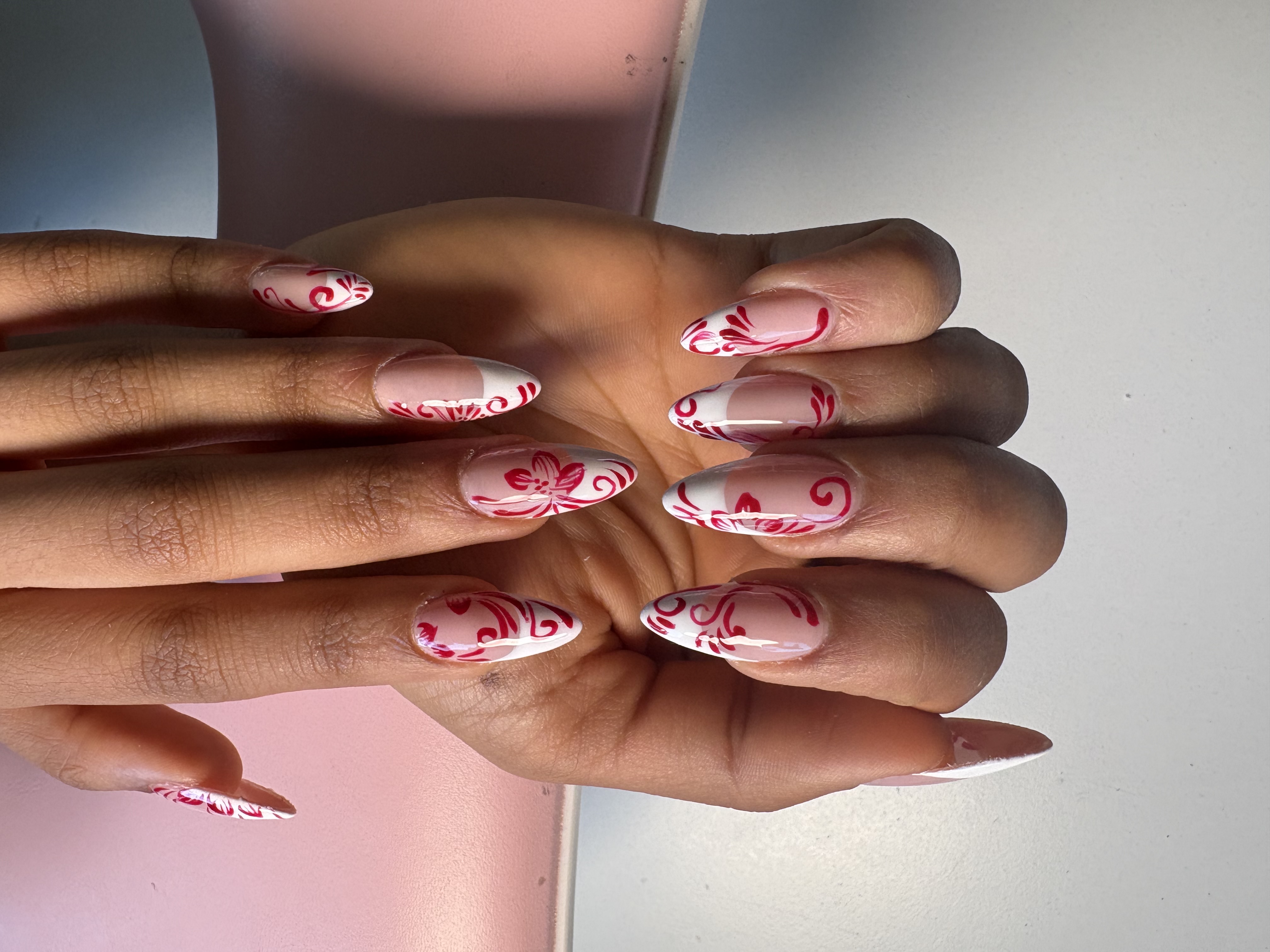 White French tips with intricate hand-painted red floral swirl linework