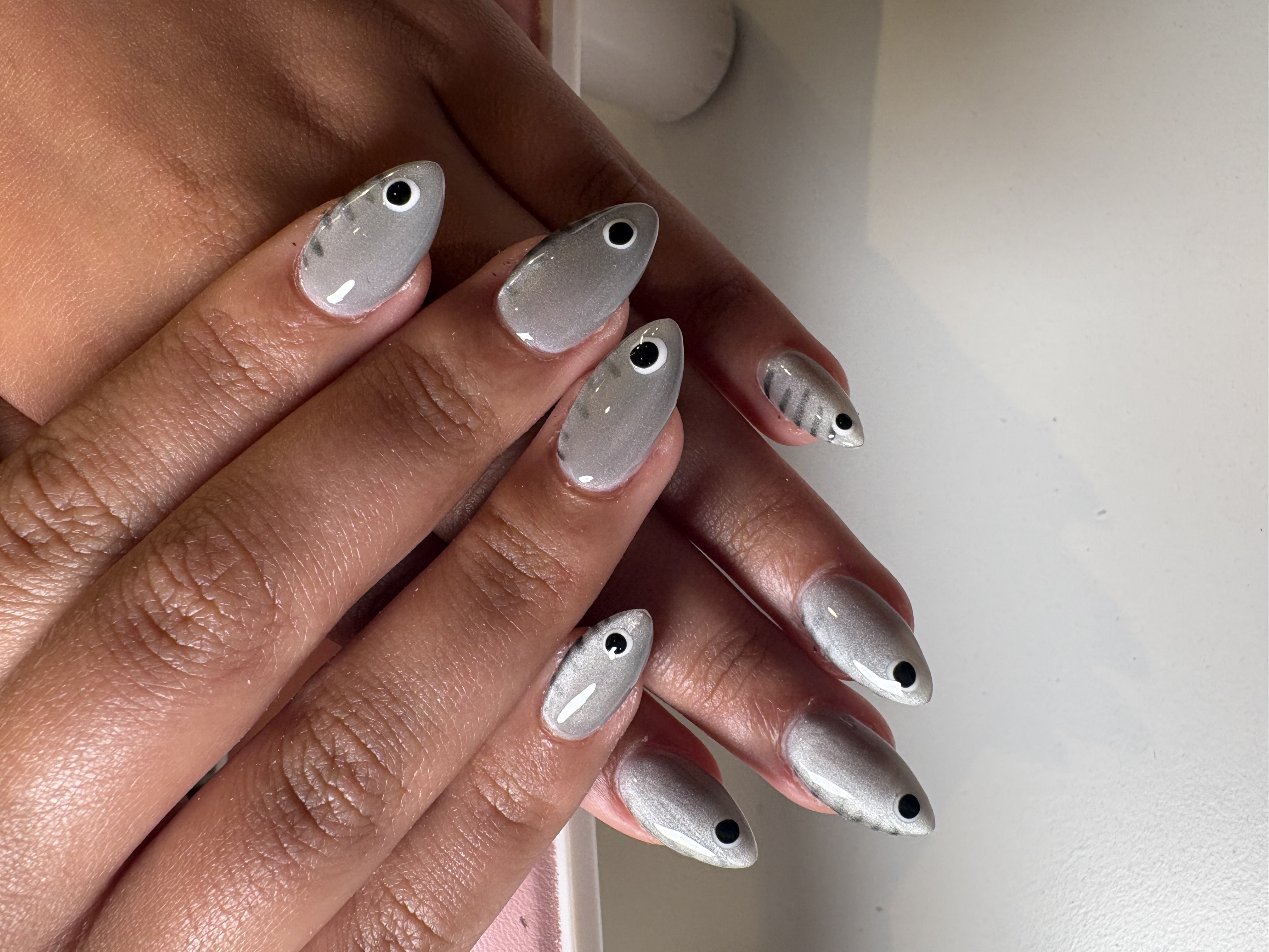 Silver almond nails in a solid metallic finish with playful black-and-white dot accents
