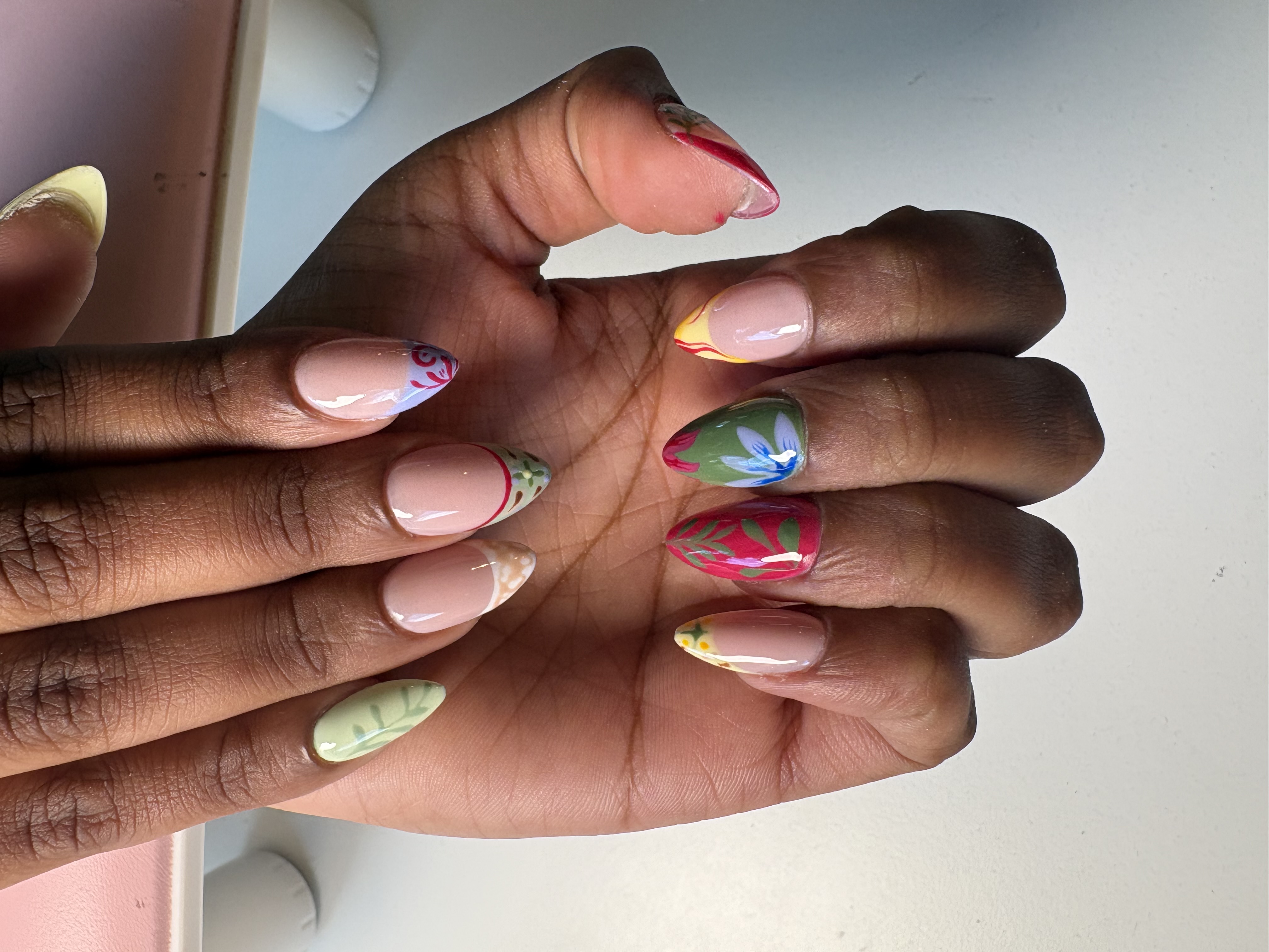 Nude almond nails with colorful hand-painted floral and leaf accent designs
